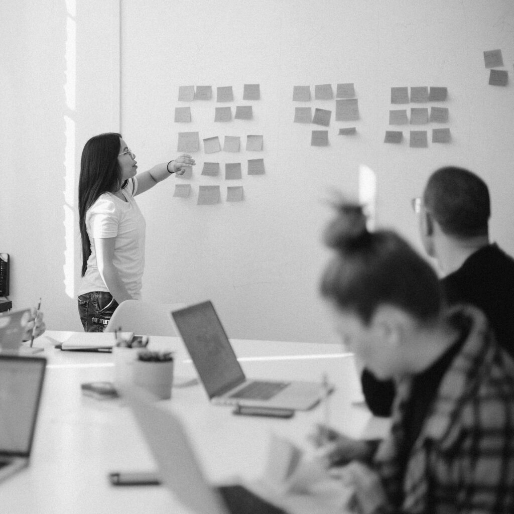 Decorative image of people participating in a workshop, working on laptops and using sticky notes