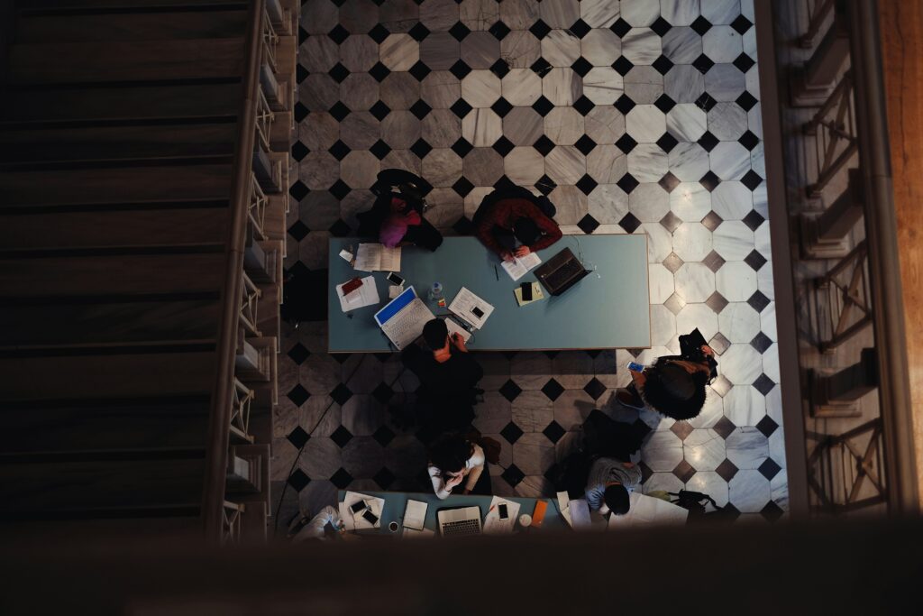 Decorative top-view image of a group of people working on various documents in a library
